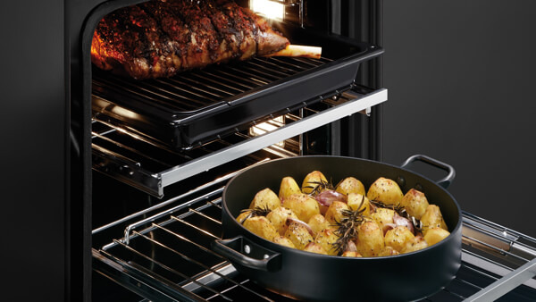 Open Multi Shelved Oven with a Tray of Lamb and Roasted Potatoes.